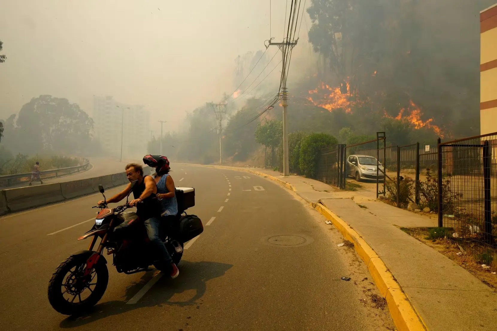 Dos personas huyen en motocicleta del incendio en Valparaíso, Chile.